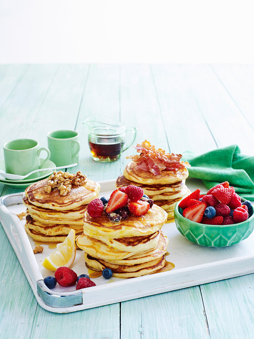 Buttermilch-Pancakes serviert mit Beeren, Nüssen und Speck