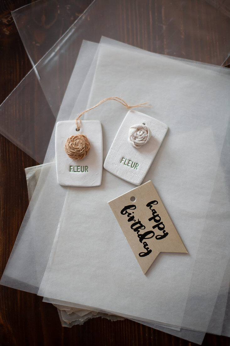 Gift tags with flower motifs and birthday greeting lying on tissue paper