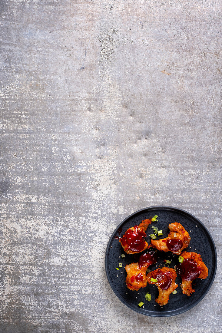 Chicken wings with a barbecue sauce and spring onions