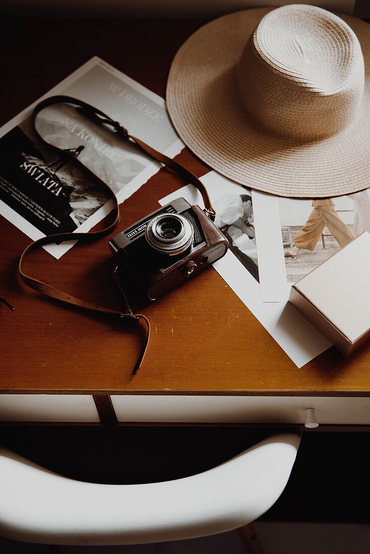Vintage camera, sun hat and pictures on table