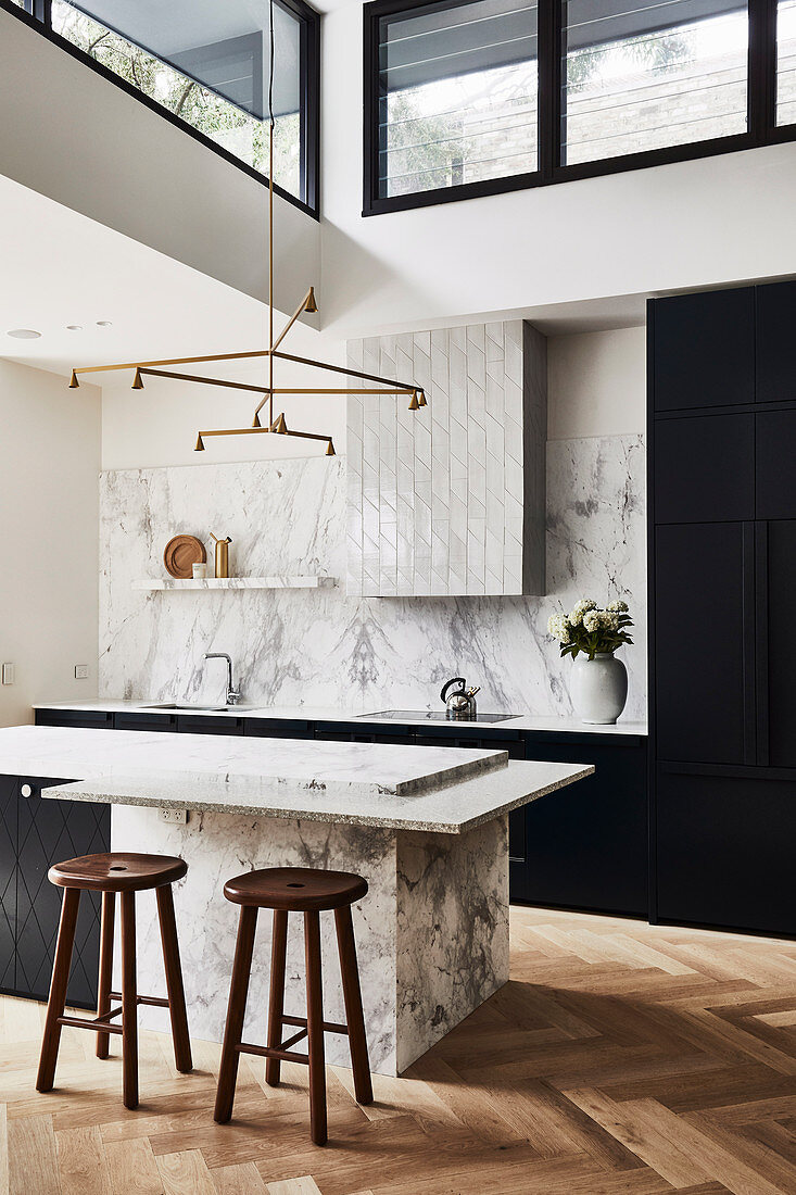 Küncheninsel in front of a kitchenette with splash protection in marble in a high room