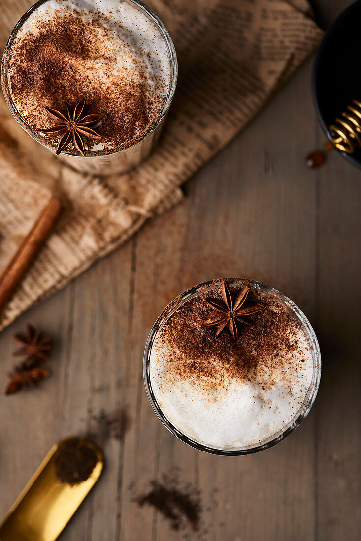 Chai Latte in Gläsern mit Milchschaum, Zimtpulver und Anisstern