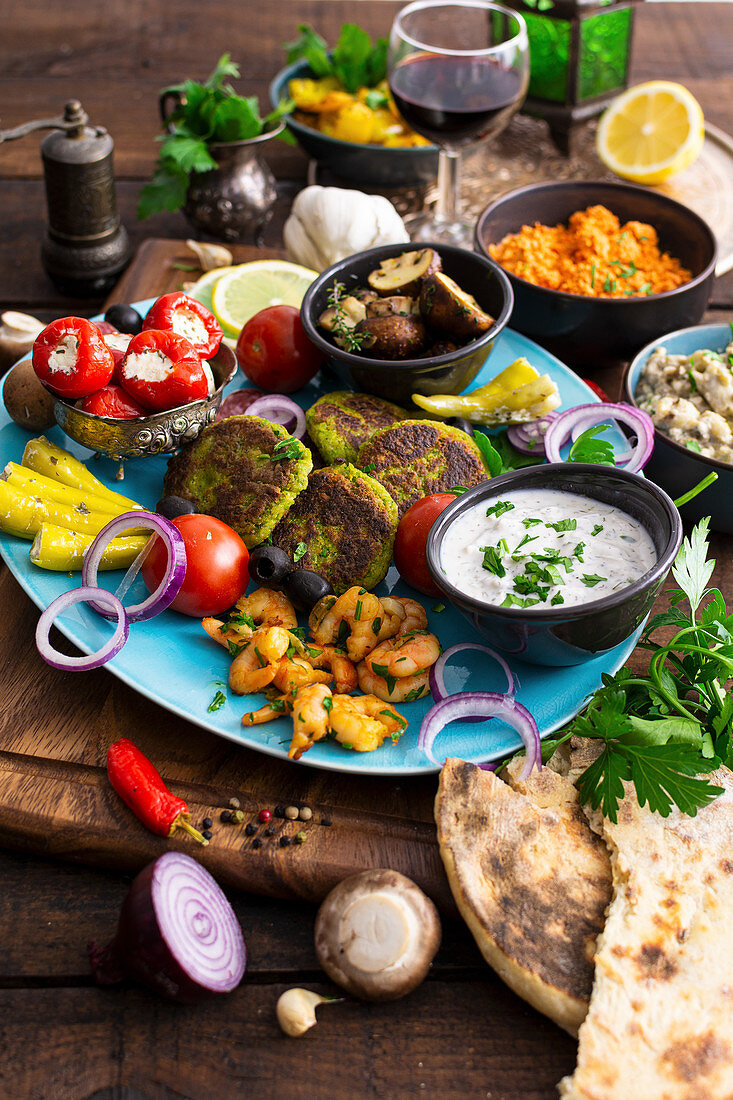 Mediterrane Antipasti mit Falafel, Garnelen, Tzatziki, Gemüse und Naan-Brot