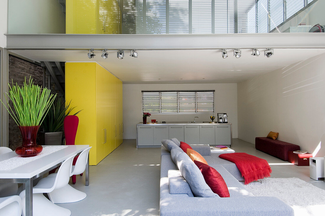 Gallery and yellow cupboards used as partitions in open-plan interior of architect-designed house