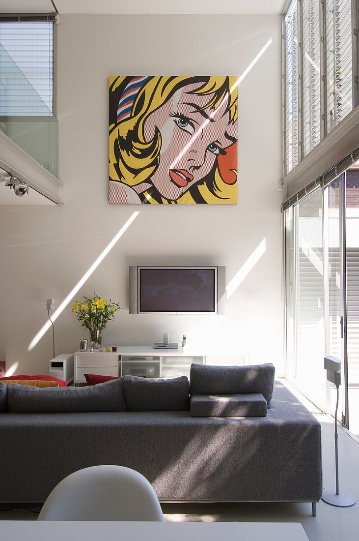 Pop-Art-Wandbild über Sitzbereich mit Sofa und Fernseher in Wohnraum mit hohen Wänden und Galerie