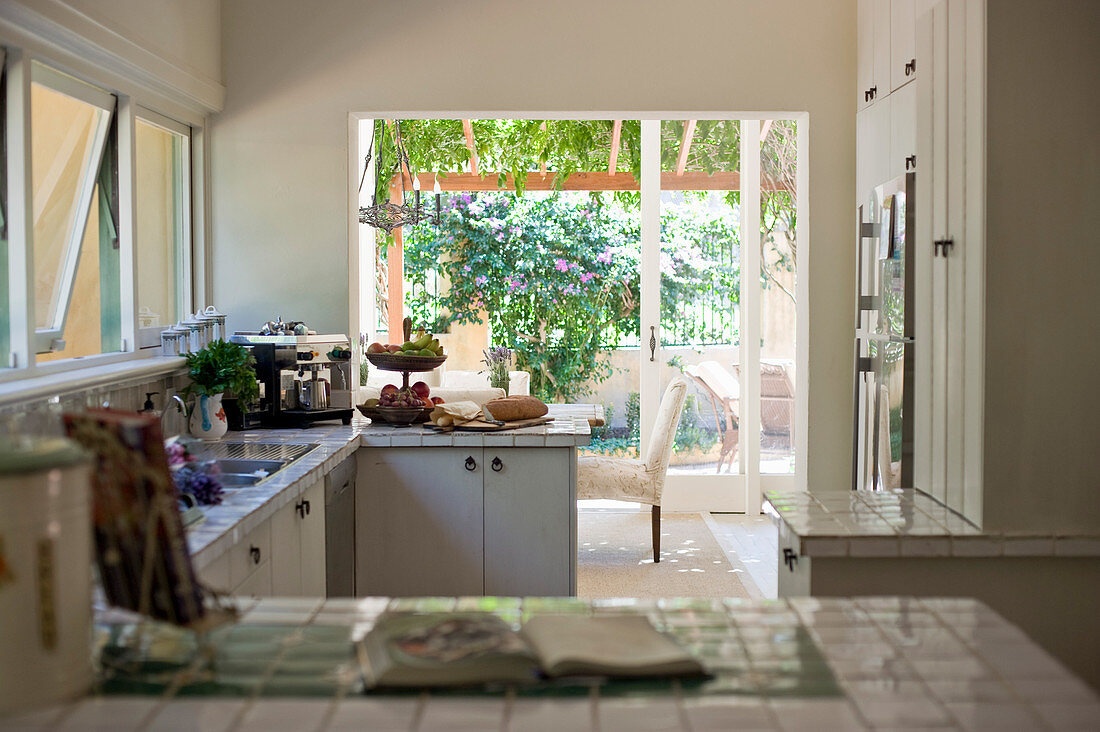 White-tiled worksurface in country-house kitchen with terrace access