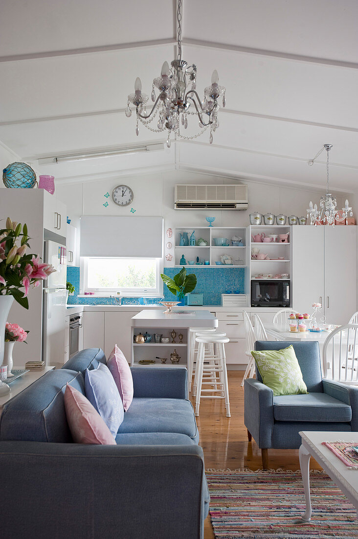 Blue-and-white interior with open-plan kitchen and seating area with couch and armchairs