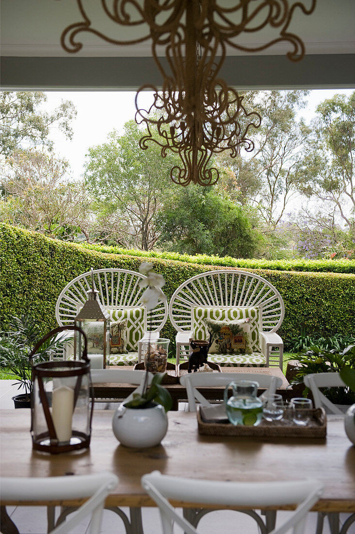 Dining table and two white peacock chairs on roofed terrace