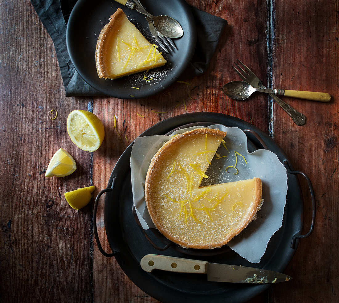 Lemon Tart with slice taken out Slice on plate with lemons