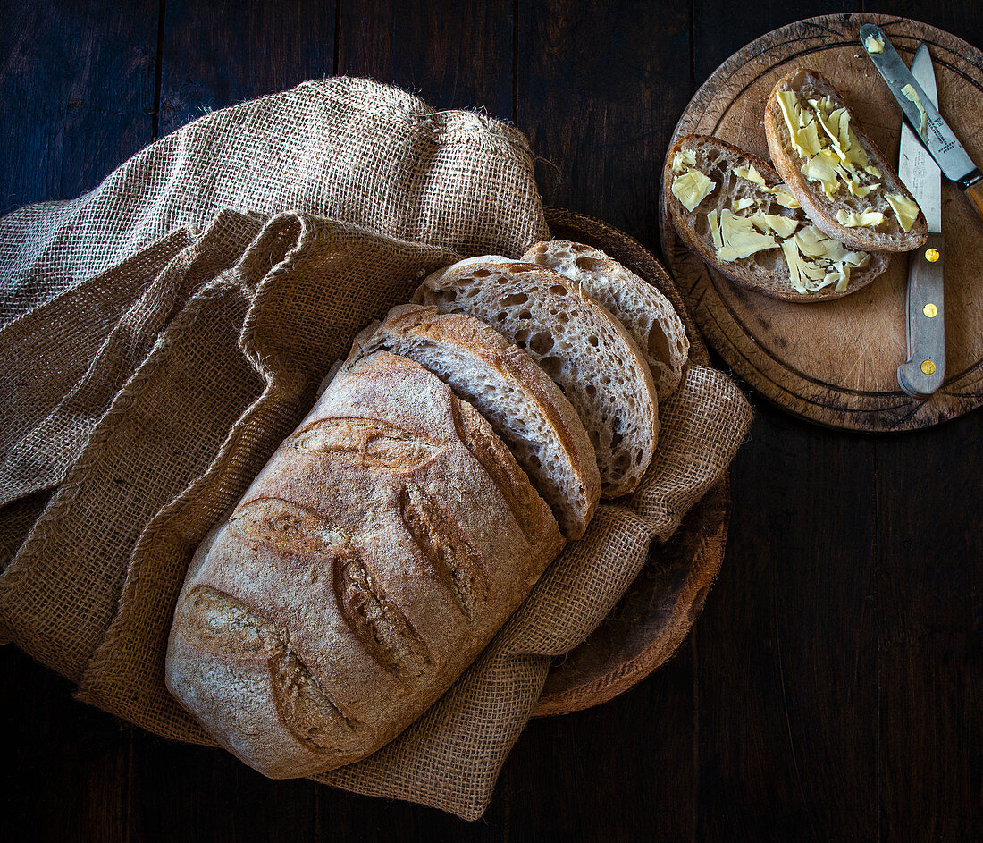 Sourdough Organic Bread in a bread basket with slices of buttered bread