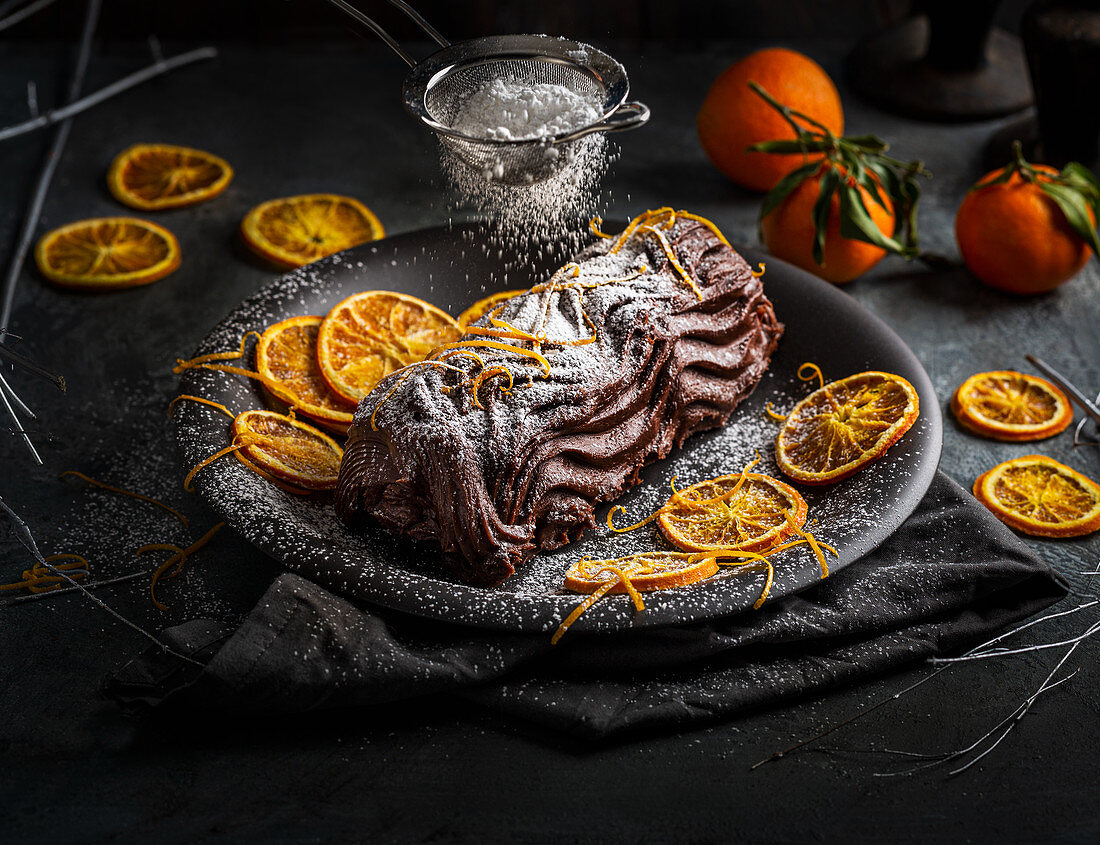 Schokoladen-Baumstammkuchen mit Orangenzesten und Puderzucker
