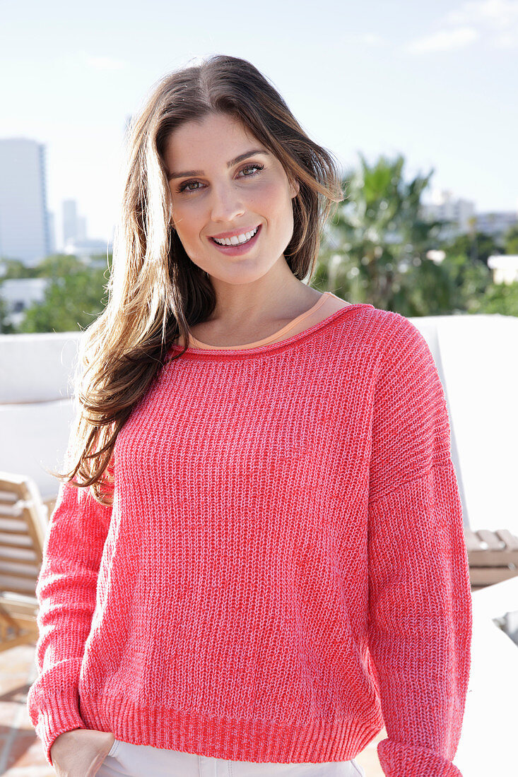 A young woman wearing a fuchsia jumper and white jeans