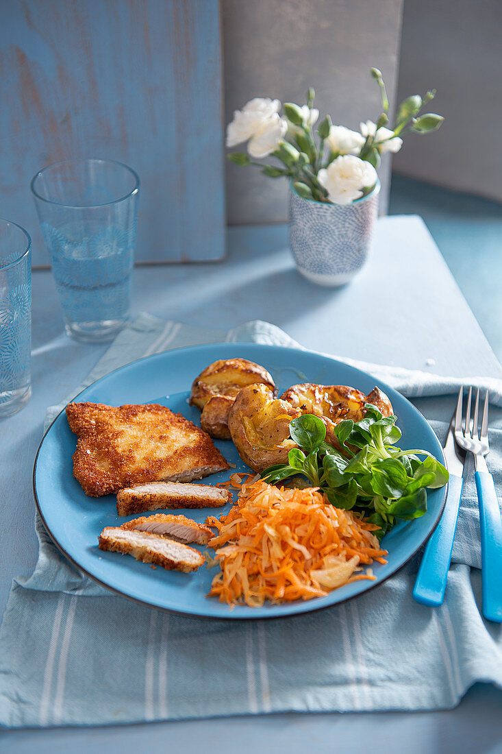 Schweineschnitzel mit Crushed Potatoes, Sauerkraut, Möhren und Feldsalat