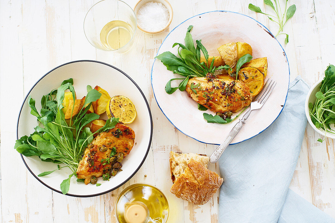 Healthy dinner with roasted chicken, potato wedges on white wooden table