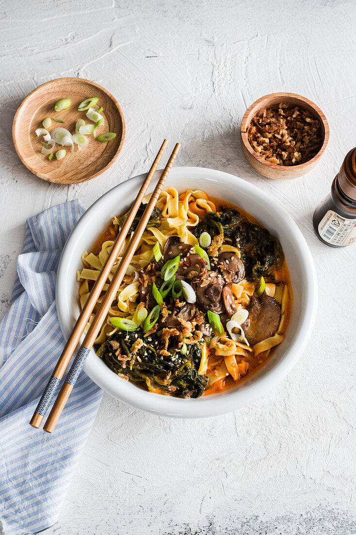 Spicy noodles soup with spinach and mushrooms