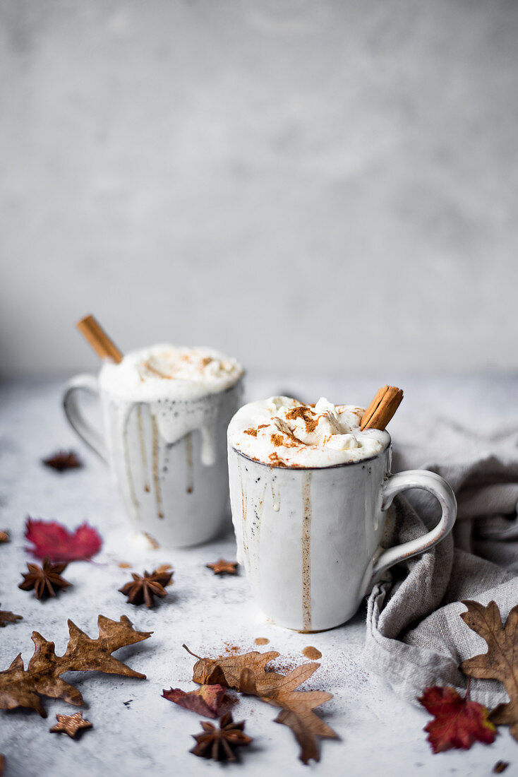 Pumpkin Spiced Latte With Whipped Cream Topping And Cinnamon Dusting Surrounded By Leaves And Spices