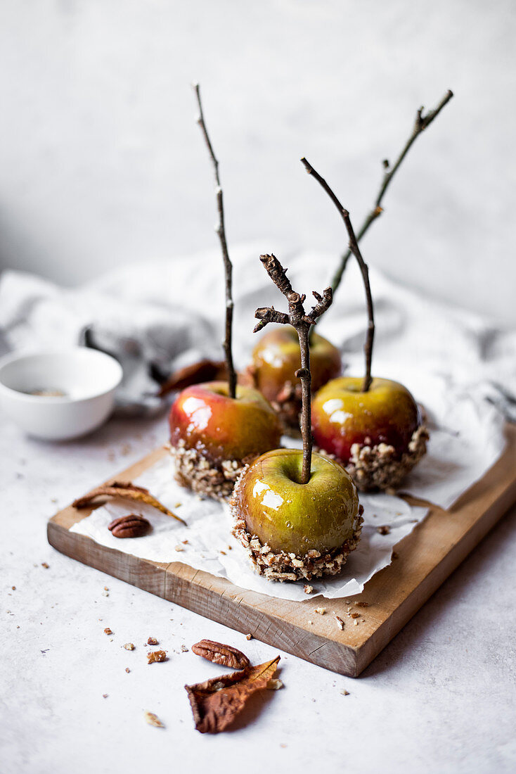 Herbstliche Karamelläpfel am Stiel mit gehackten Pekannüssen