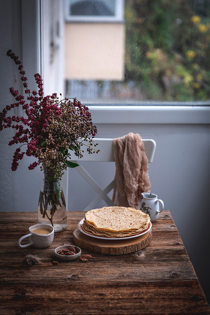Stack of crepes and a cup of coffee on rustic wooden table