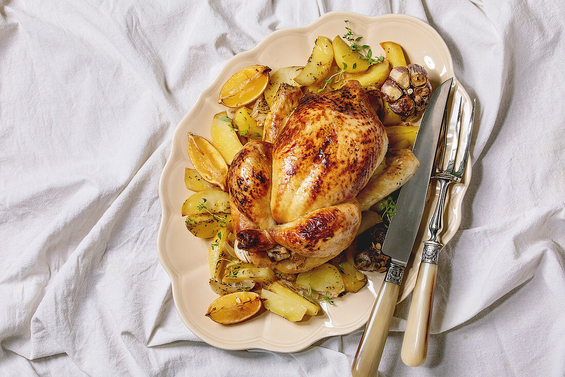 Whole roasted chicken with potatoes, garlic and lemons