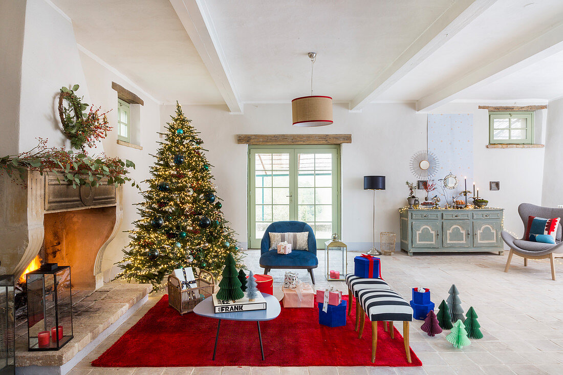 Weihnachtsbaum und Möbel in Blau und Rot vorm offenen Kamin