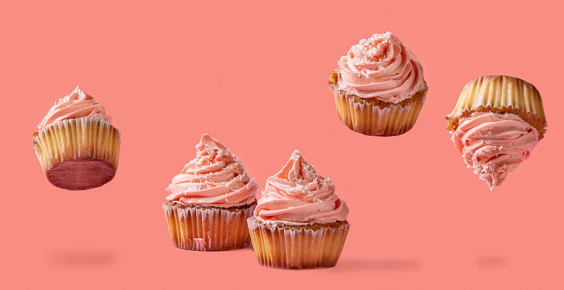 Homemade levitation cupcakes with pink buttercream and coconut flakes over red pink background