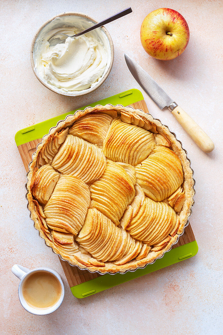 Apple tart with whipped cream and a cup of coffee on the table