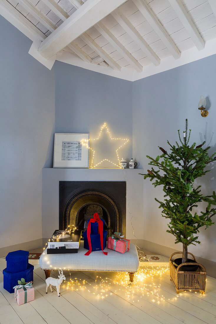 Christmas decorations and gifts in front of corner fireplace in room with pale blue walls