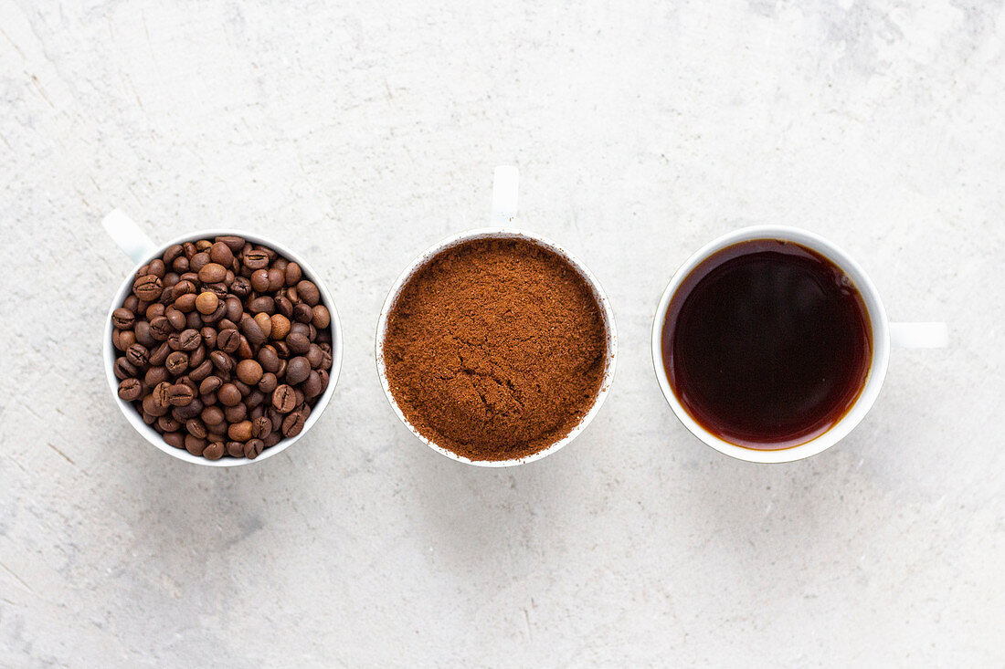 Kaffeetassen mit Kaffeebohnen, gemahlenem Kaffee und Filterkaffee