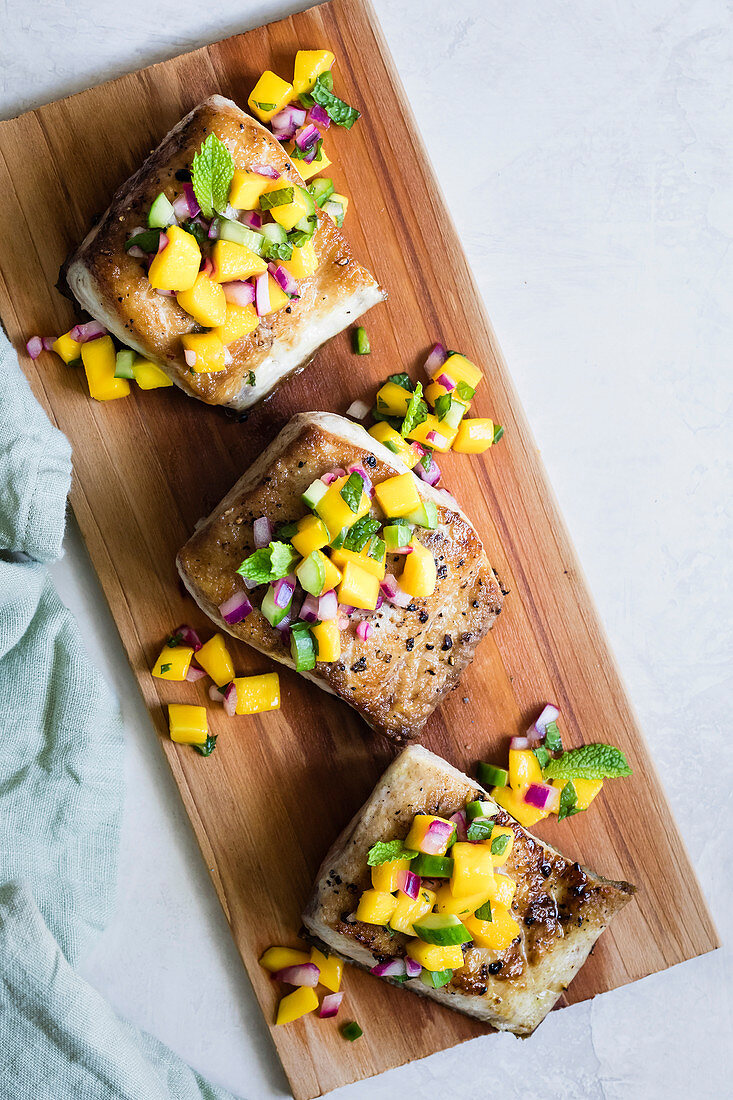 Pan fried fish with a mango salad topping