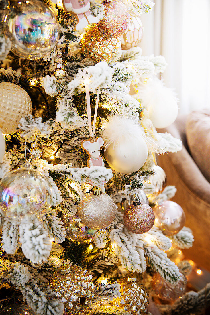 Christmas tree decorated with artificial snow and pink and champagne baubles
