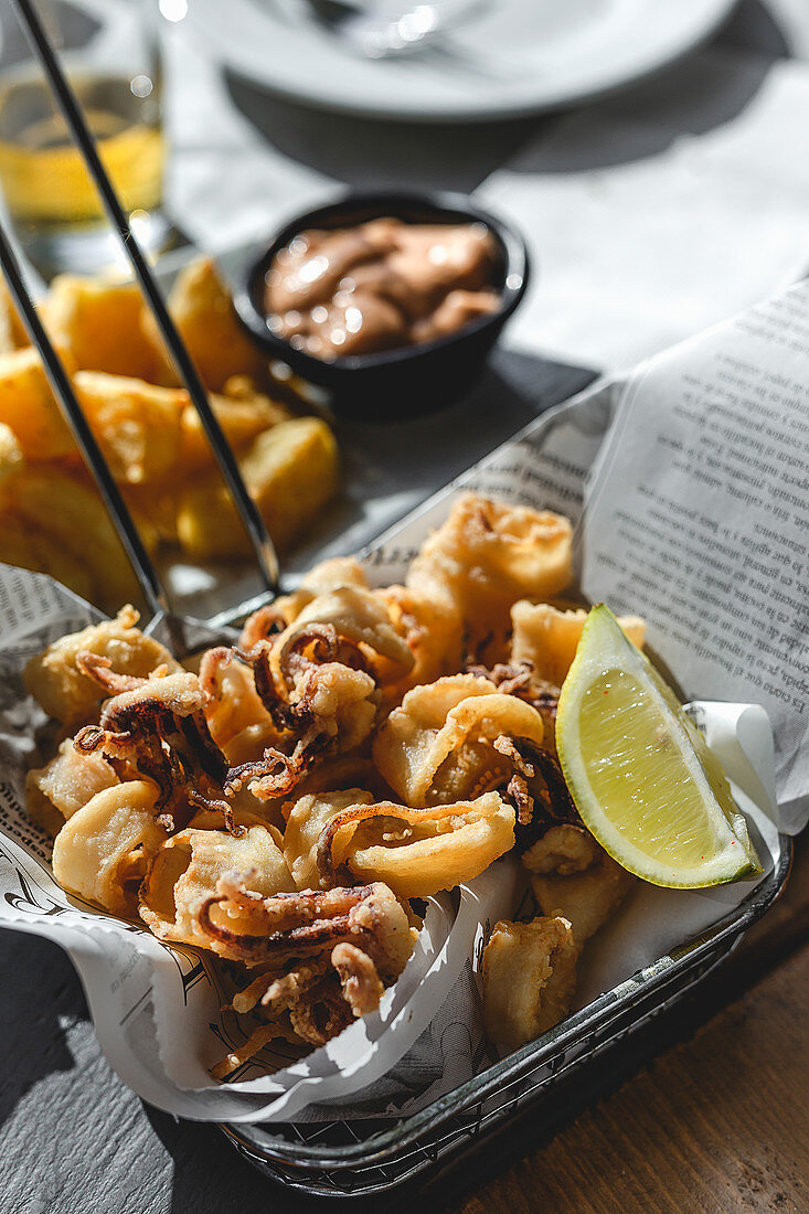 Fried small octopuses served in fryer basket with lemon