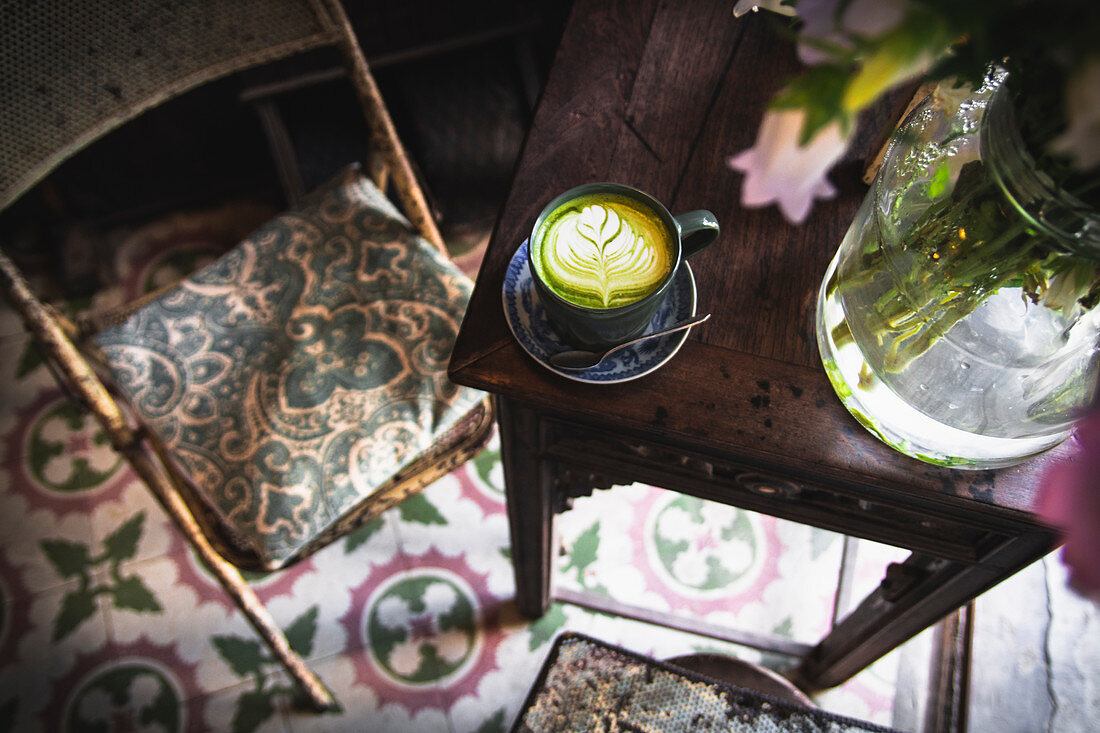 A matcha latte on a coffee table with a chair