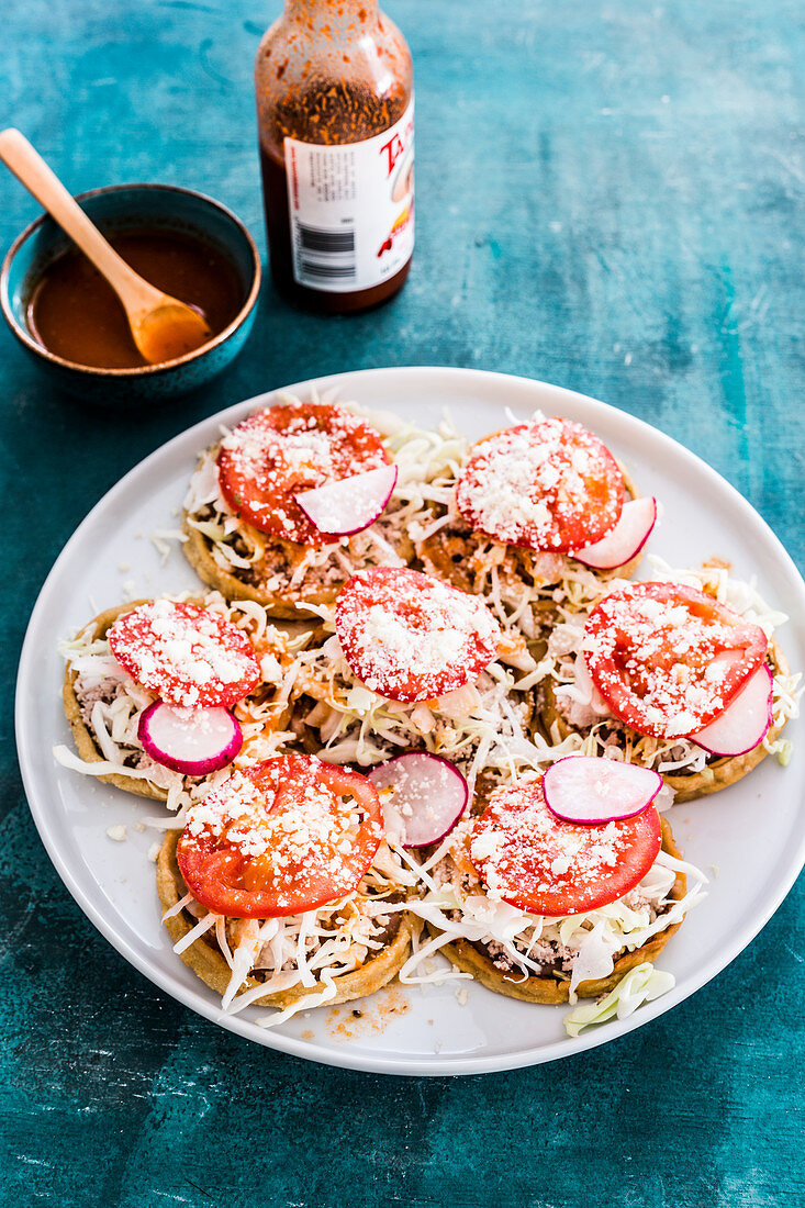 Maistortillas mit Bohnenpüree, Fleisch, Zwiebeln, Kohl, frischen Tomaten, Käse und Radieschen