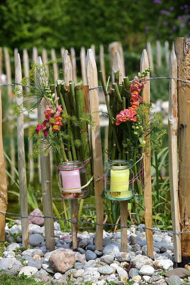 Candle lanterns made from knotweed, preserving jars and flowers hung on paling fence