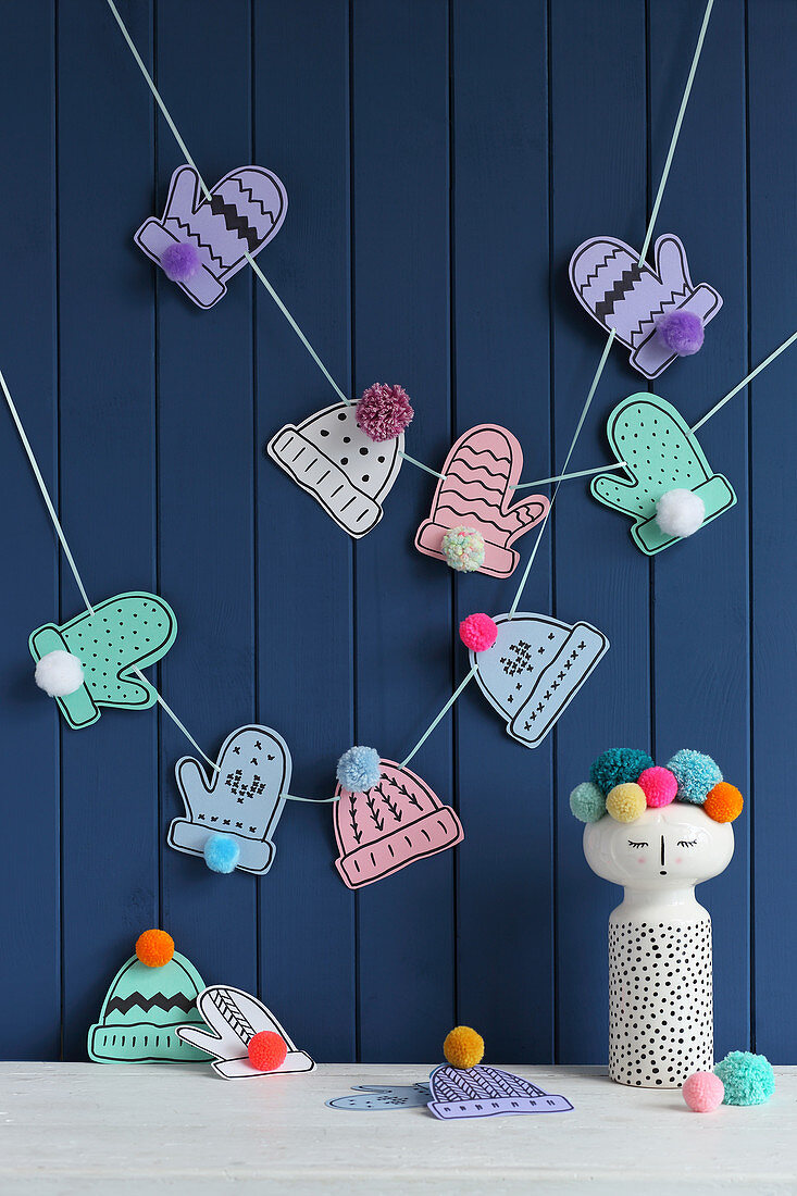 Garland of paper gloves and hats with pompoms