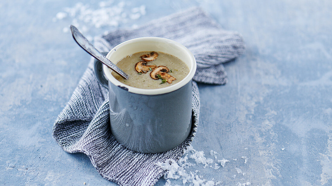 Wintry mushroom cream soup in a metal cup with a spoon