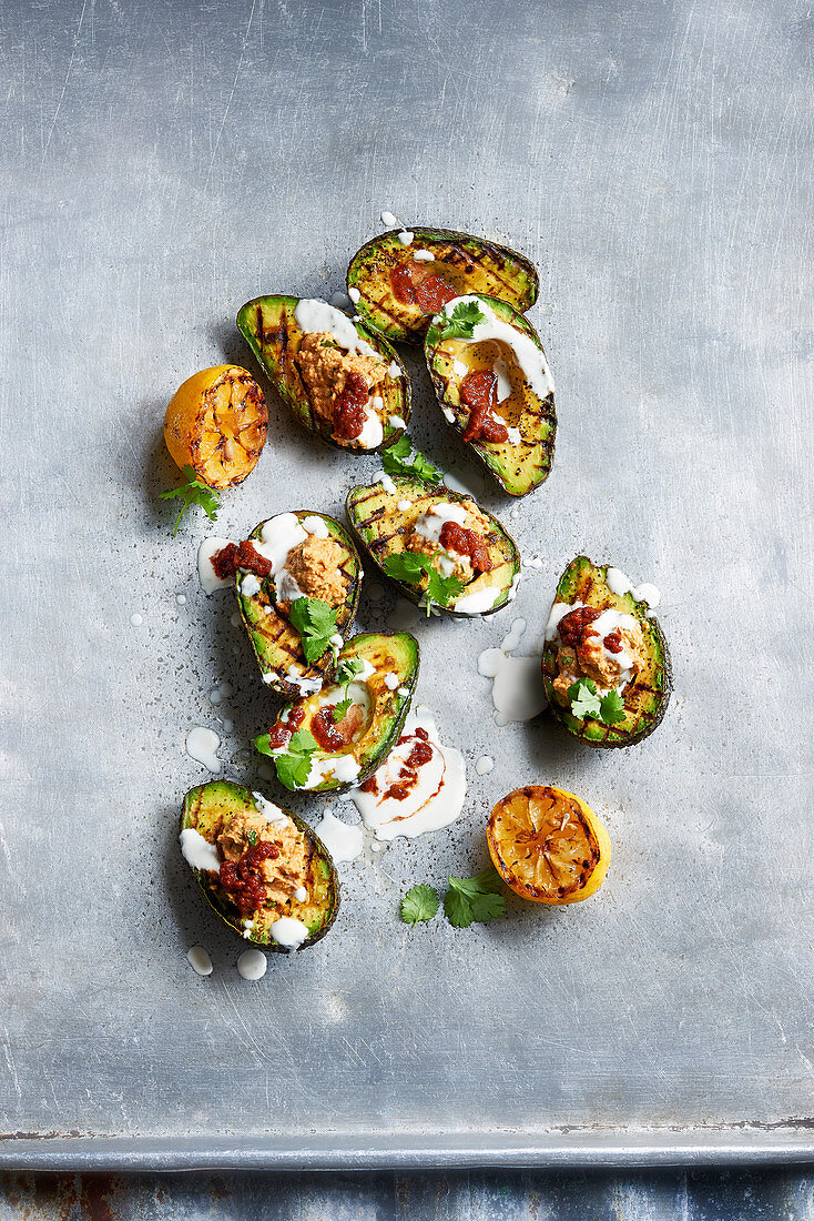 Grilled avocado halves with harissa, hummus and tahini yogurt