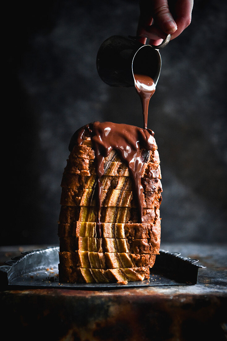 Melted chocolate flows on stacked slices of banana bread
