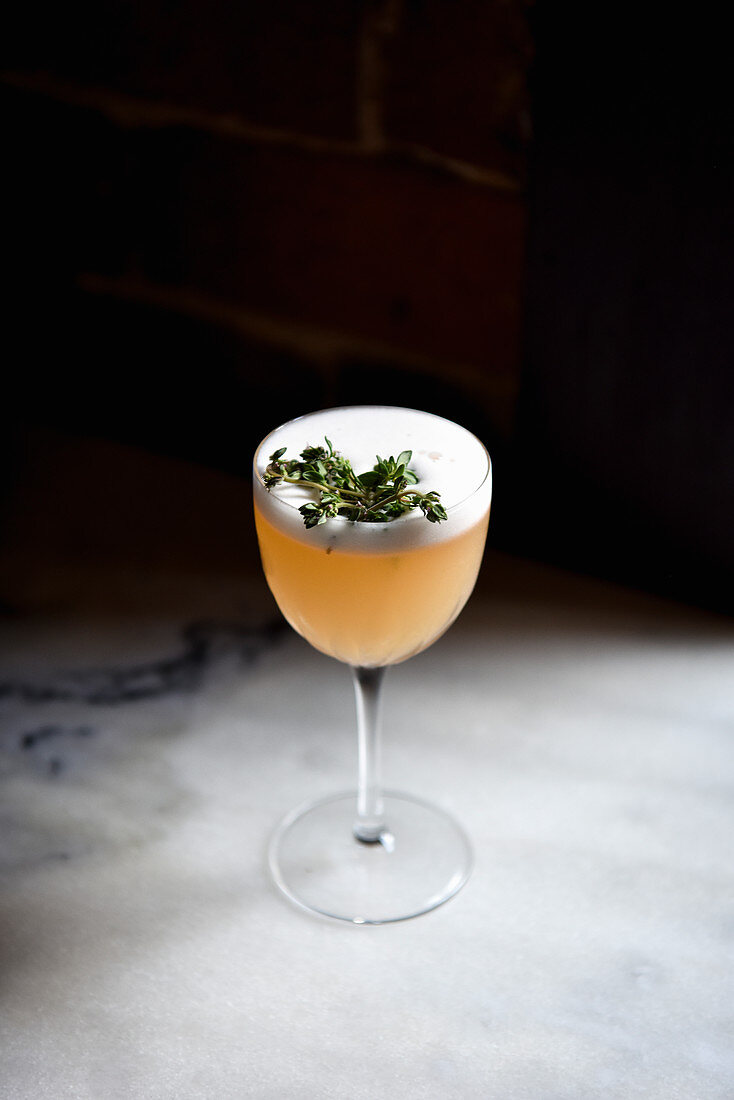 A cocktail decorated with herbs against a dark background
