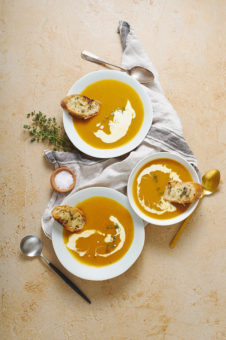 Flatlay with plates of squash soup with thyme, cream and cheese croutons