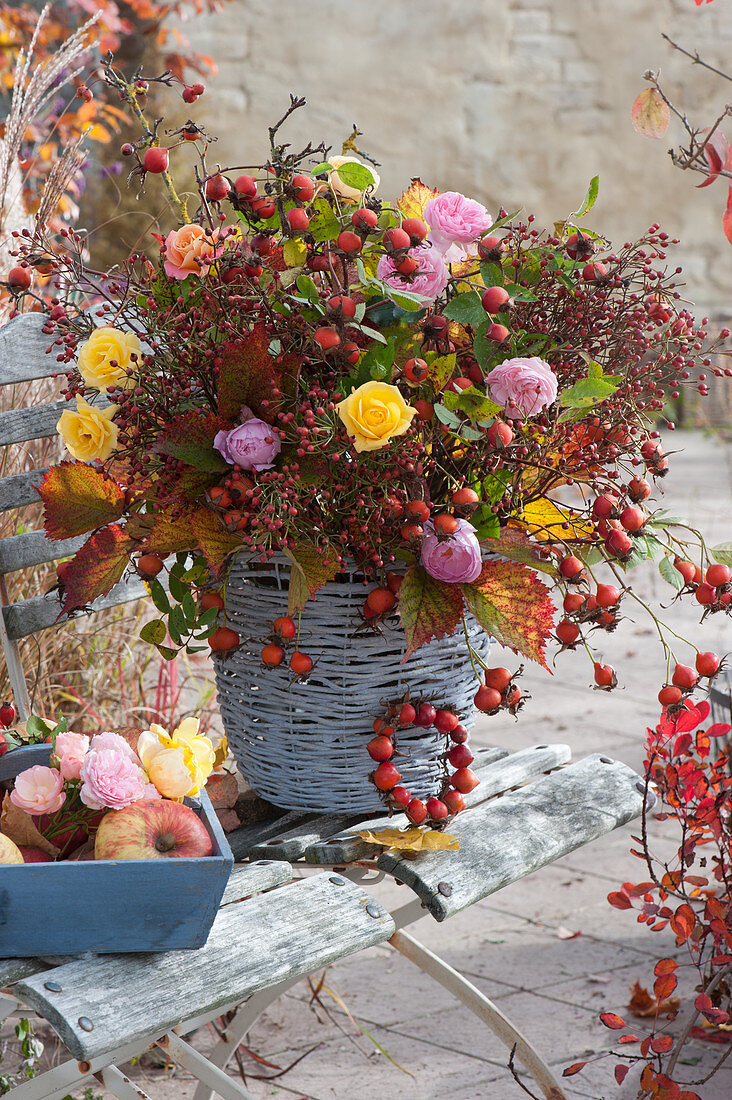 Autumn bouquet of rose hips and roses in wicker vase