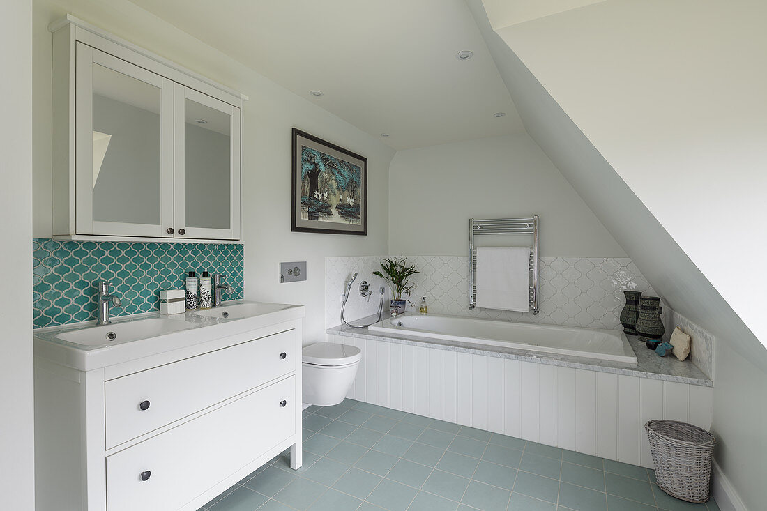 Washstand, mirrored wall cabinet and bathtub in attic bathroom
