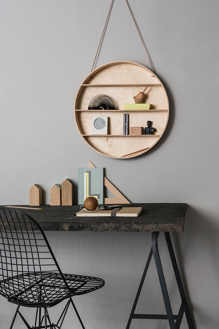 Desk with black top, metal chair and round set of shelves hung on wall