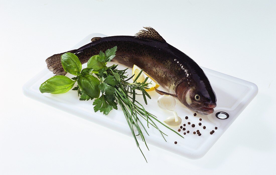 Trout on chopping board with herbs and spices
