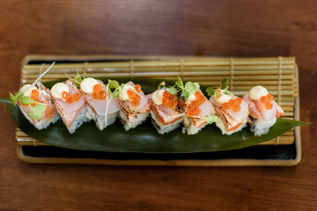 Tasty rolls with rice and fish garnished with caviar and cheese sauce