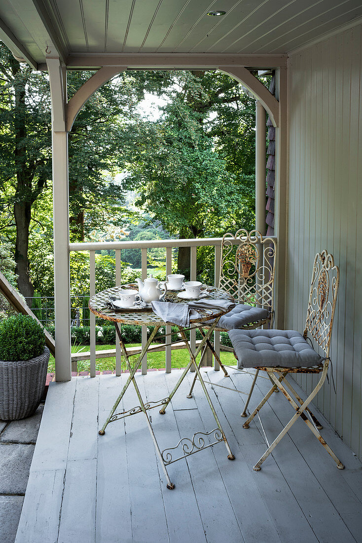 Wrought iron table and chairs on Victorian terrace, set in woodland, Surrey, England