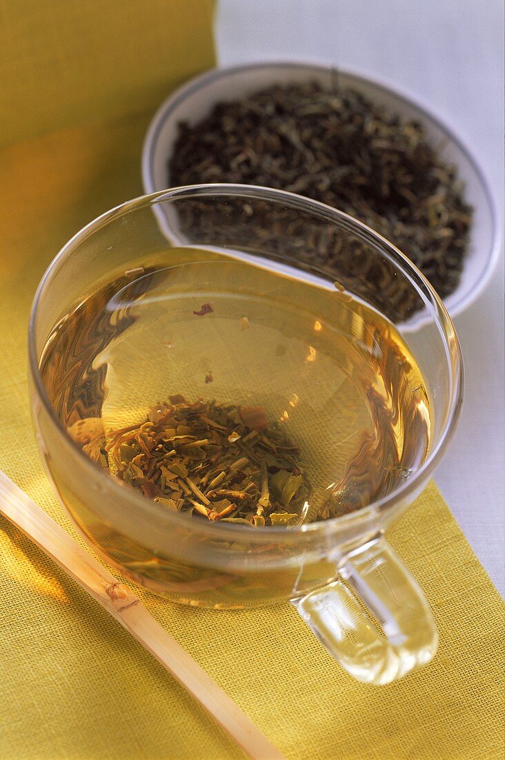 Grüner Darjeeling Tee in Glastasse & Blätter im Schälchen