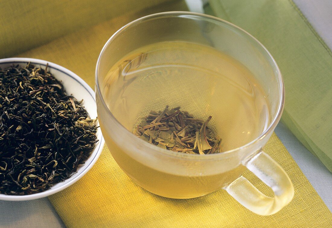 Grüner Darjeeling Tee in Glastasse & Blätter im Schälchen