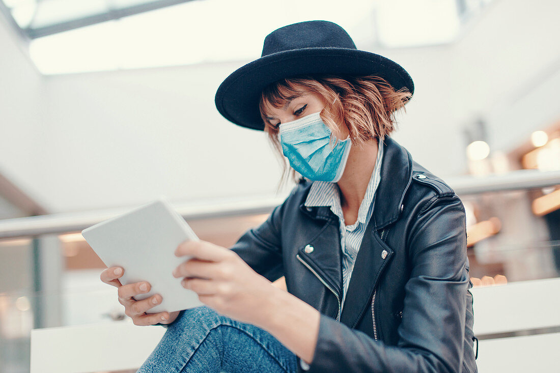Woman in face mask reading on digital tablet