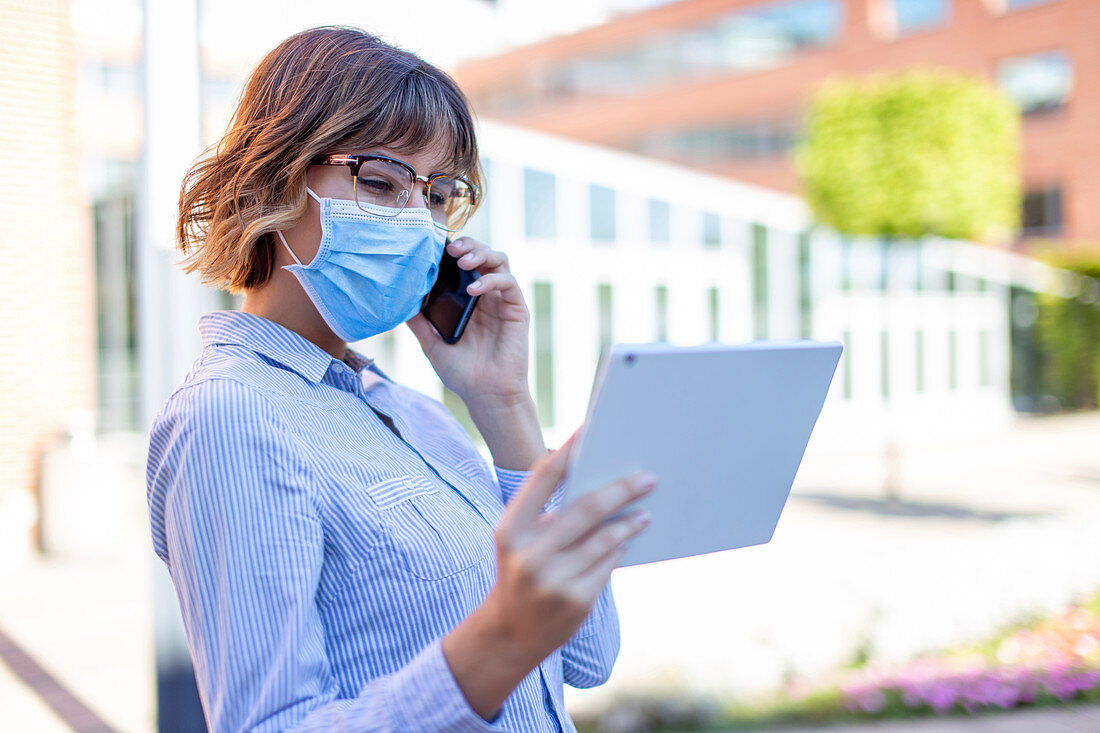 Businesswoman in face mask making phone call